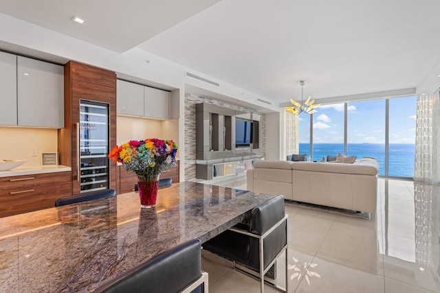 kitchen featuring dark stone counters, a water view, white cabinetry, and an inviting chandelier