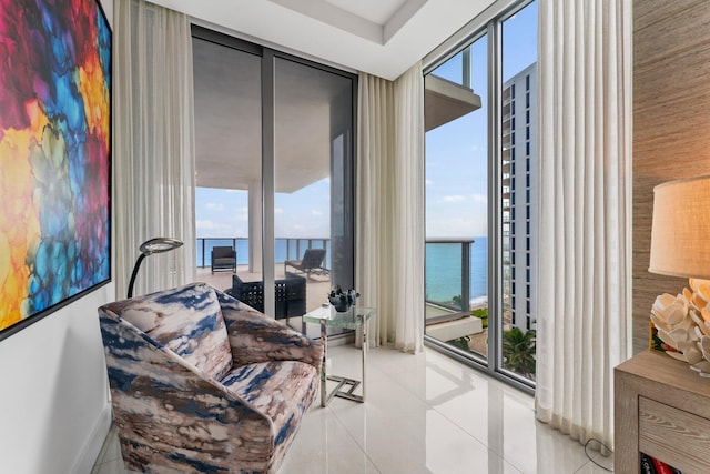 sitting room with a healthy amount of sunlight, a water view, and floor to ceiling windows