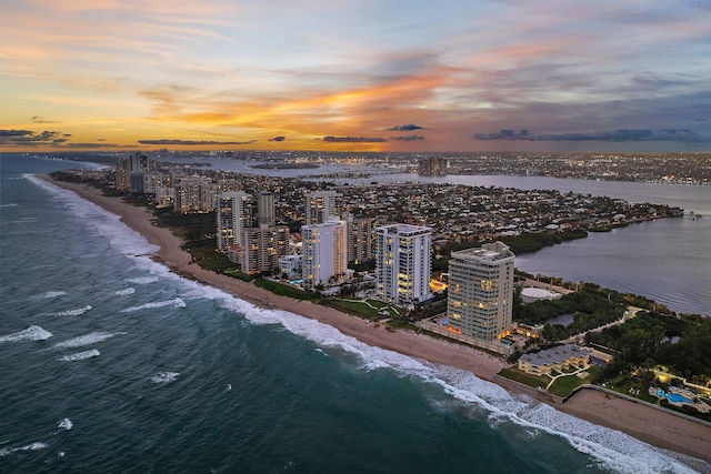 aerial view at dusk with a water view and a beach view