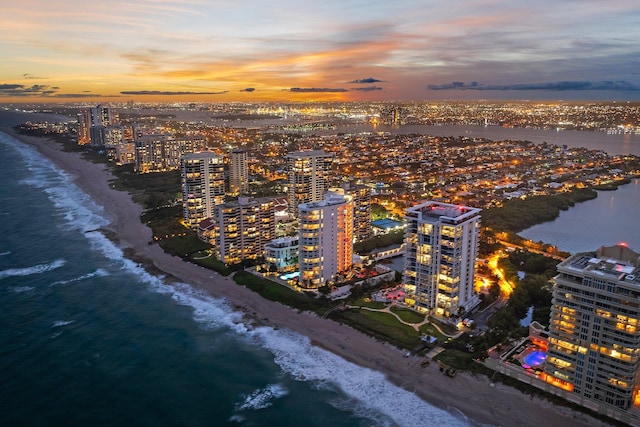 aerial view at dusk with a water view and a beach view