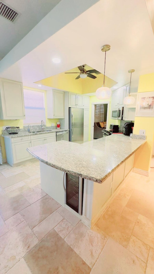 kitchen featuring appliances with stainless steel finishes, a kitchen breakfast bar, kitchen peninsula, pendant lighting, and ceiling fan