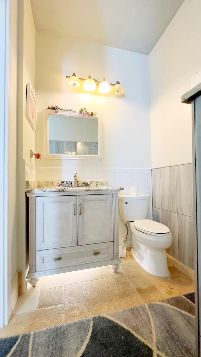 bathroom with vanity, tile walls, and toilet