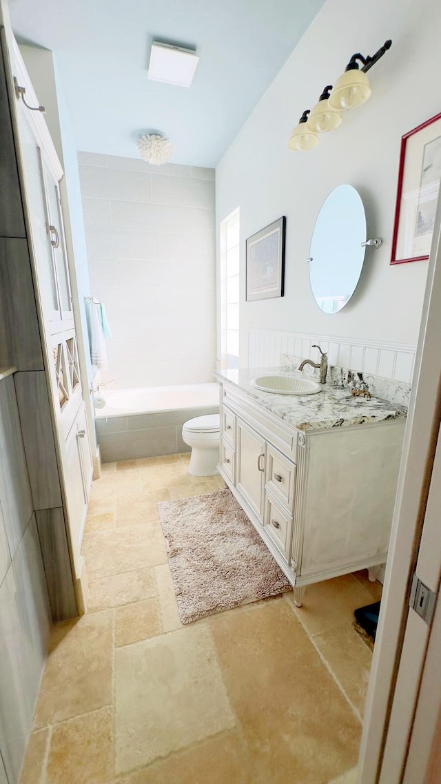 bathroom featuring vanity, toilet, and a relaxing tiled tub