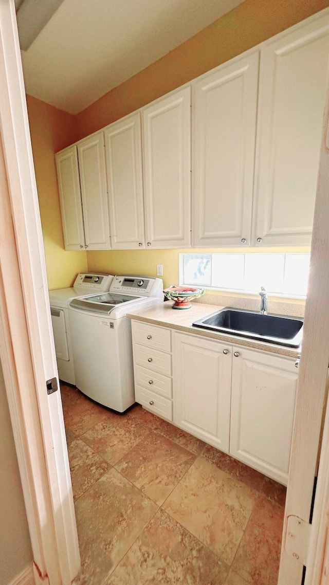 laundry area with cabinets, washer and dryer, and sink