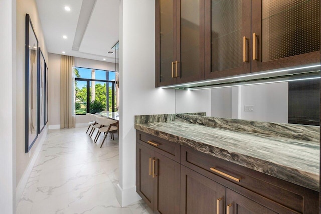 kitchen with dark stone counters and dark brown cabinetry