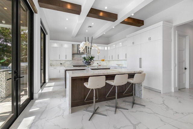 kitchen featuring a large island, decorative backsplash, light stone counters, and white cabinets