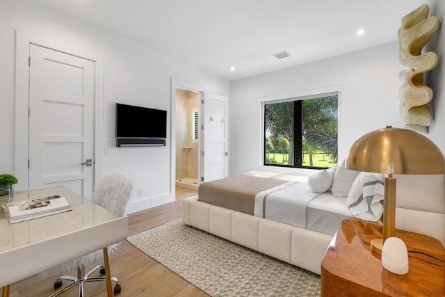 bedroom featuring hardwood / wood-style flooring and ensuite bathroom