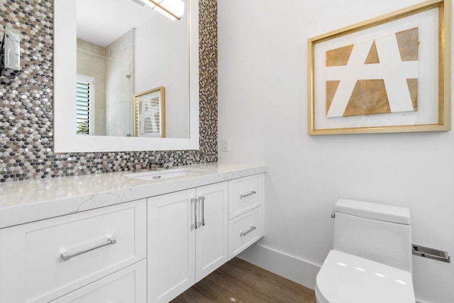 bathroom featuring tiled shower, wood-type flooring, toilet, vanity, and backsplash