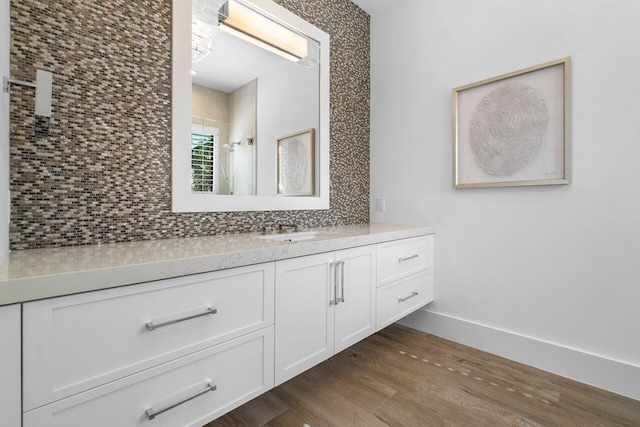 bathroom with walk in shower, hardwood / wood-style flooring, vanity, and decorative backsplash