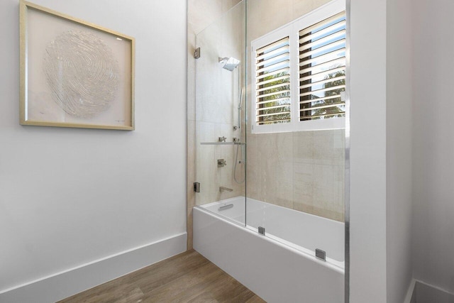 bathroom featuring hardwood / wood-style flooring and bath / shower combo with glass door