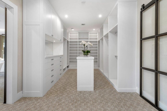 walk in closet featuring light colored carpet and a barn door