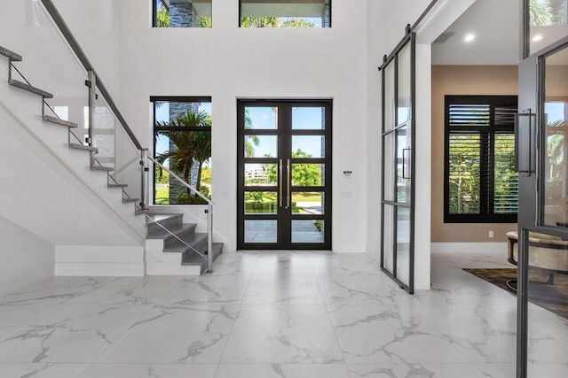 entryway featuring a high ceiling, a wealth of natural light, french doors, and a barn door