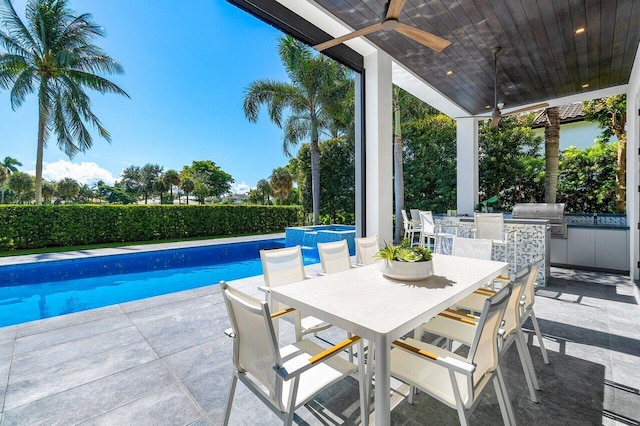 view of swimming pool with an outdoor kitchen, ceiling fan, area for grilling, and a patio area