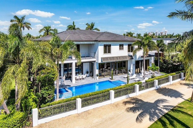 rear view of property with a balcony, a fenced in pool, and a patio area