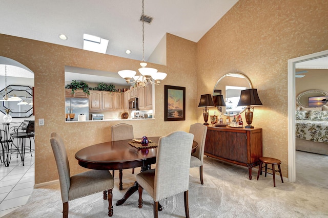 dining area featuring light carpet, a notable chandelier, and high vaulted ceiling