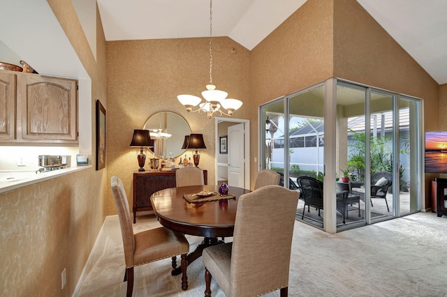 dining area with light colored carpet, an inviting chandelier, and high vaulted ceiling