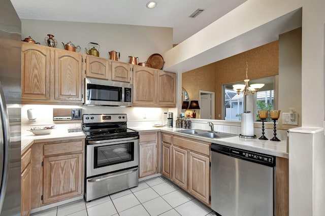 kitchen featuring lofted ceiling, light tile patterned floors, appliances with stainless steel finishes, light brown cabinetry, and an inviting chandelier