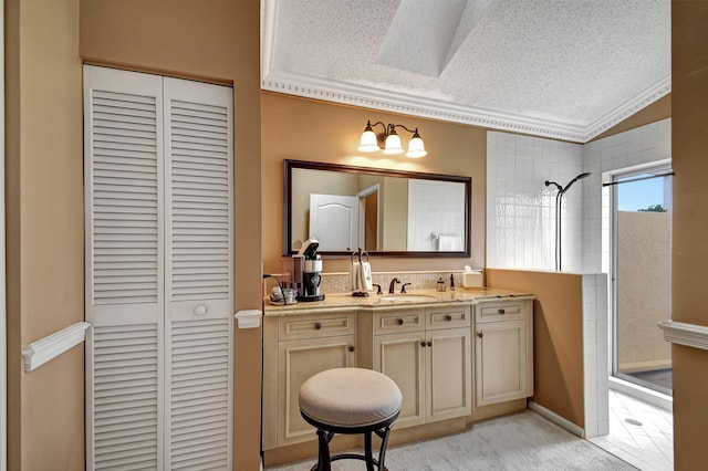 bathroom with vanity, a textured ceiling, crown molding, and a tile shower