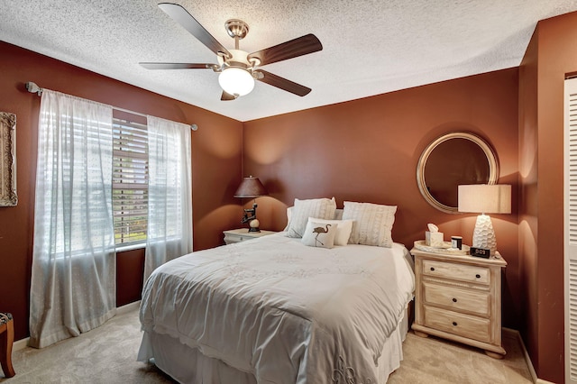 bedroom with ceiling fan, light colored carpet, and a textured ceiling