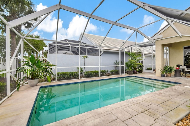 view of pool with glass enclosure and a patio