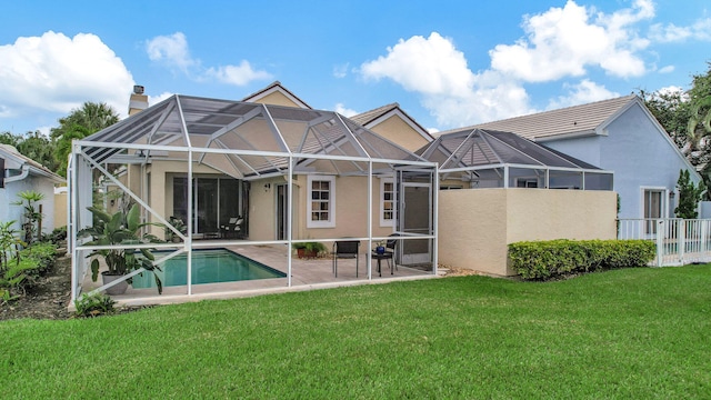 back of property with glass enclosure, a patio area, and a yard