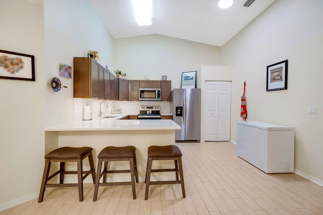 kitchen featuring kitchen peninsula, a breakfast bar area, sink, and stainless steel appliances