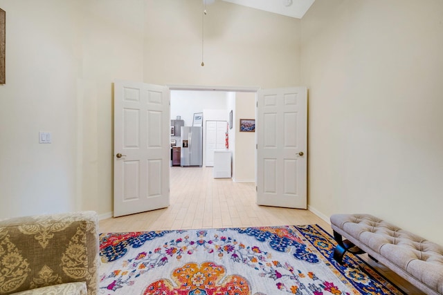 bedroom with stainless steel refrigerator with ice dispenser, wood-type flooring, and high vaulted ceiling