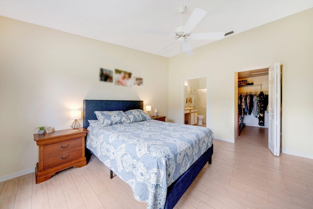 bedroom featuring a spacious closet, a closet, light hardwood / wood-style flooring, ceiling fan, and ensuite bath