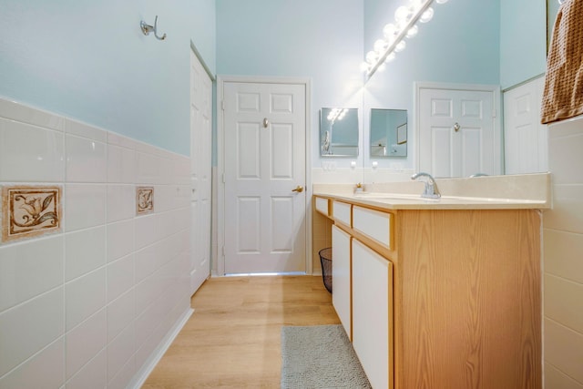 bathroom with tile walls, vanity, and hardwood / wood-style floors