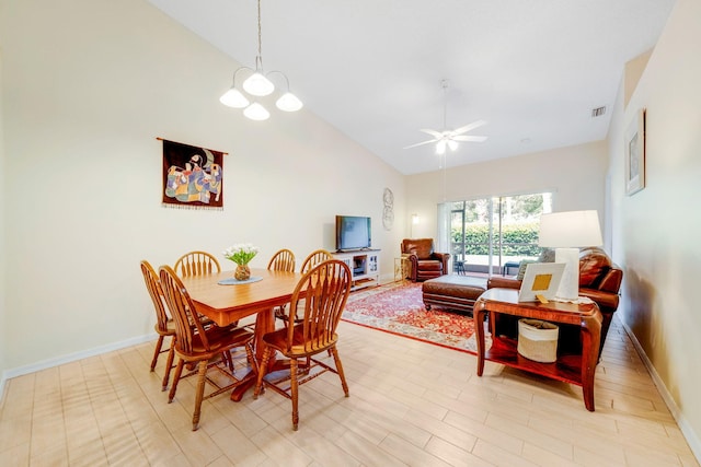 dining area featuring light wood-type flooring, ceiling fan with notable chandelier, and high vaulted ceiling