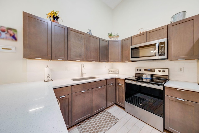 kitchen featuring high vaulted ceiling, stainless steel appliances, tasteful backsplash, and sink