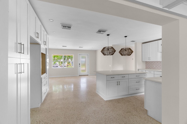 kitchen featuring backsplash, decorative light fixtures, and white cabinets