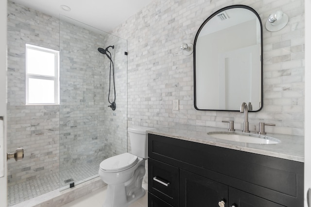 bathroom with tile walls, tiled shower, vanity, and toilet