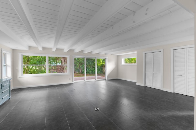 unfurnished bedroom with two closets and beamed ceiling