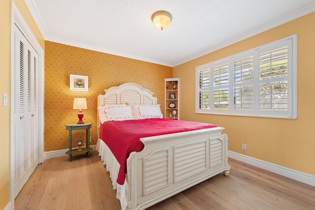 bedroom featuring light wood-type flooring, crown molding, and a closet