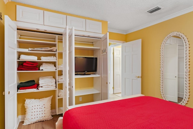 bedroom featuring hardwood / wood-style flooring, ornamental molding, and a textured ceiling