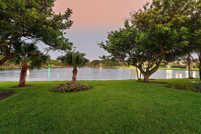 back house at dusk featuring a lawn and a patio