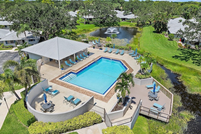 view of swimming pool featuring a patio, a water view, and a lawn