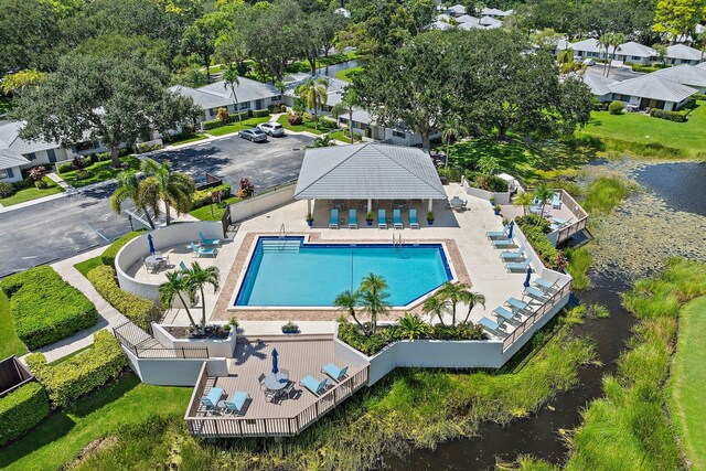 view of pool featuring a lawn, a water view, and a patio