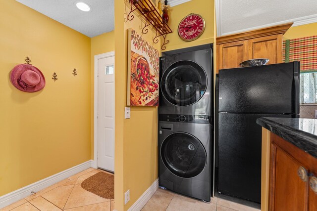 laundry room with a textured ceiling, stacked washer / drying machine, and light tile patterned floors