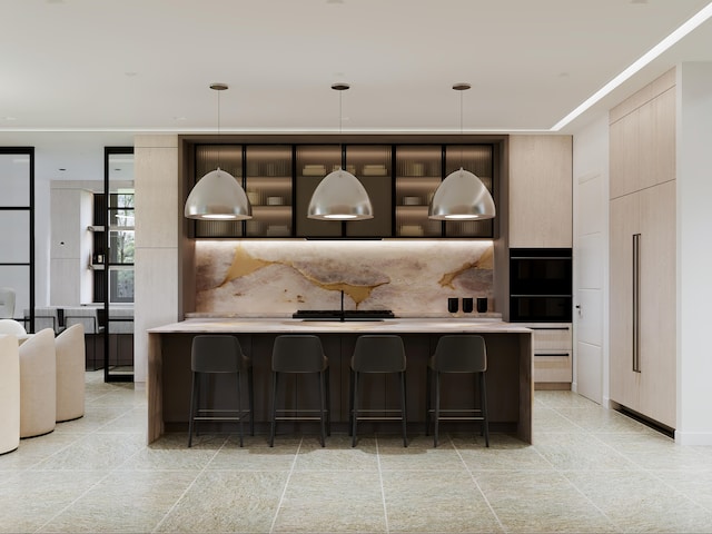 kitchen with a kitchen island with sink, decorative light fixtures, a kitchen bar, and tasteful backsplash