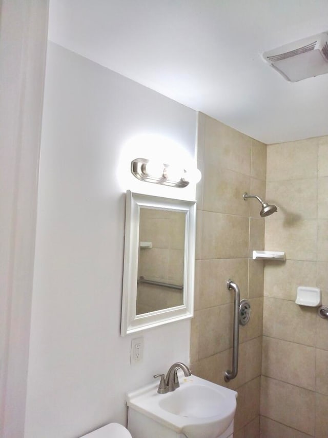 bathroom featuring a tile shower, toilet, and sink