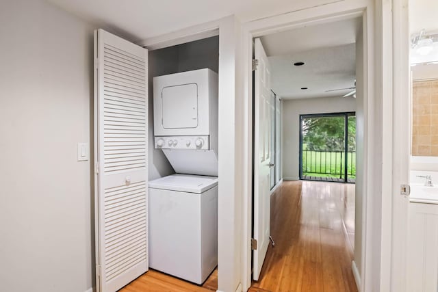 clothes washing area with ceiling fan, light hardwood / wood-style floors, and stacked washer and dryer