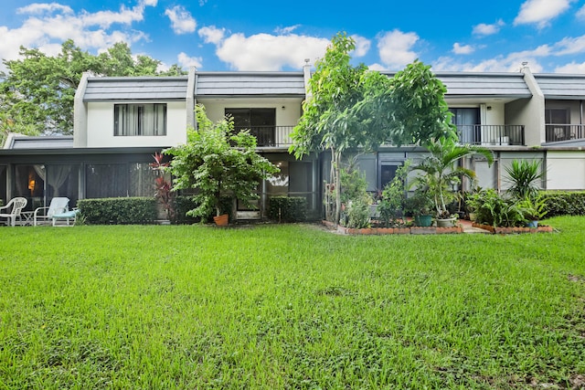 view of front of property featuring a front yard and a balcony