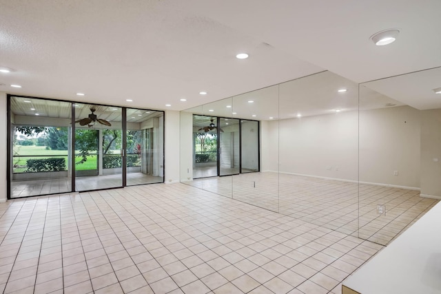 spare room with expansive windows, light tile patterned floors, and ceiling fan