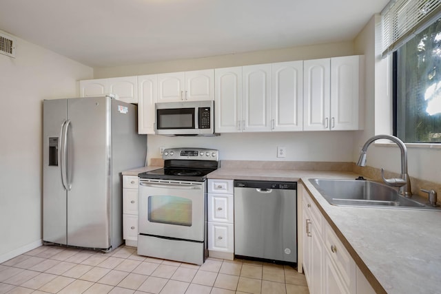 kitchen featuring stainless steel appliances, white cabinets, light tile patterned floors, and sink