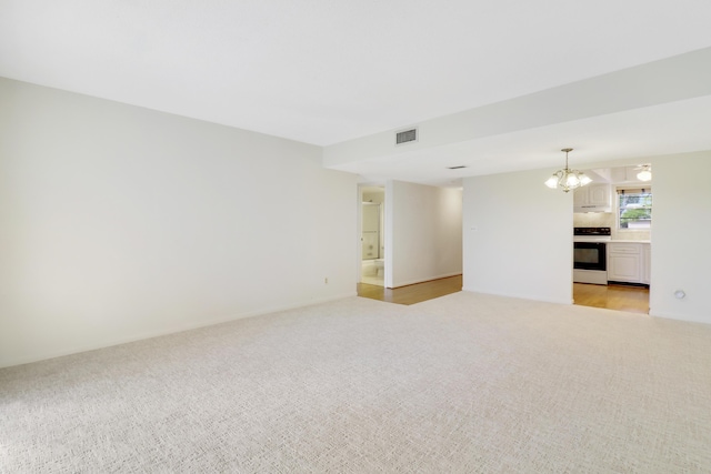 carpeted empty room with a chandelier