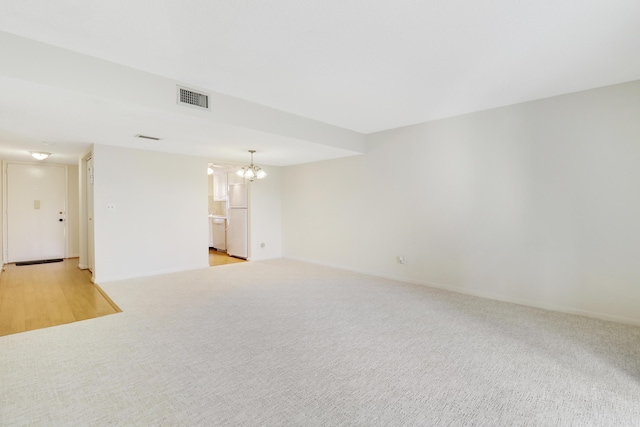 unfurnished living room featuring light carpet and a notable chandelier