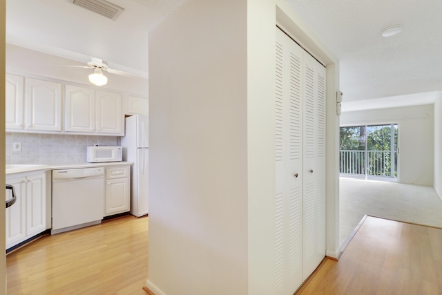 kitchen with white cabinetry, tasteful backsplash, ceiling fan, white appliances, and light hardwood / wood-style floors