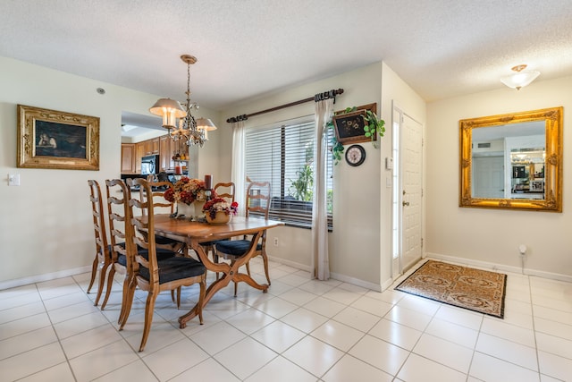 dining area with light tile patterned flooring, an inviting chandelier, and a textured ceiling